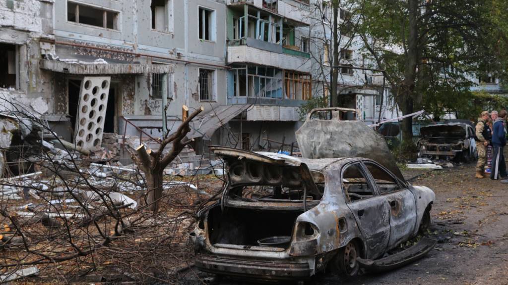 ARCHIV - Verbrannte Autos und beschädigte Wohngebäude sind nach einem russischen Angriff in Saporischschja zu sehen. Foto: Kateryna Klochko/AP/dpa
