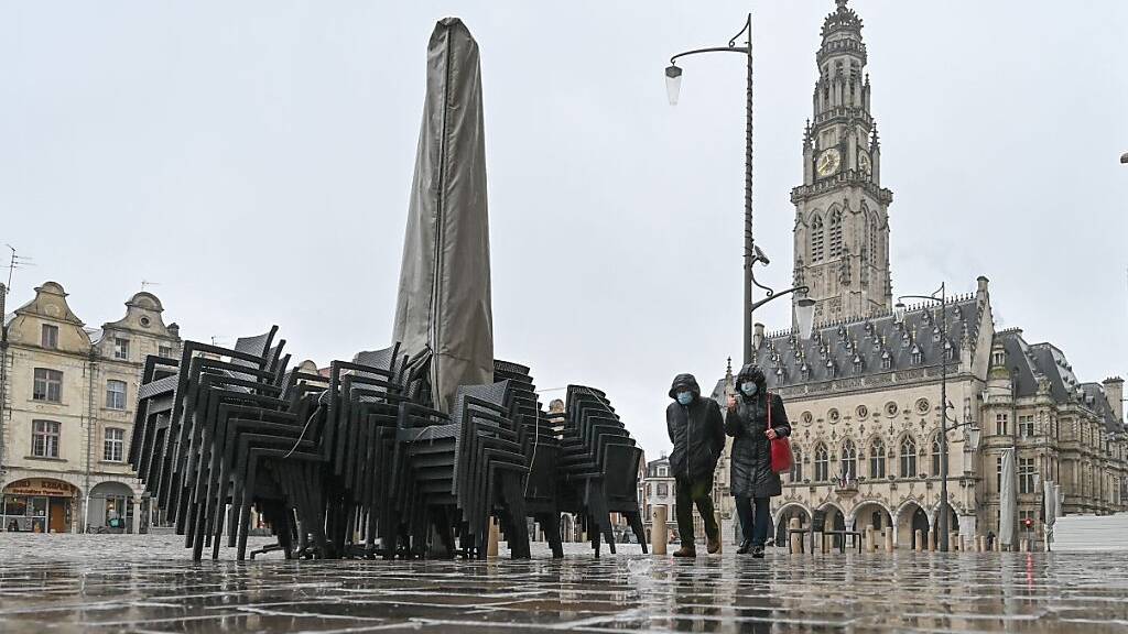Passanten gehen auf dem Place des Heros vor dem Glockenturm Beffroi d'Arras und dem Rathaus, bevor im Departement Pas-de-Calais ein erster Corona-Lockdown für das Wochenende in Kraft tritt. Foto: Denis Charlet/AFP/dpa