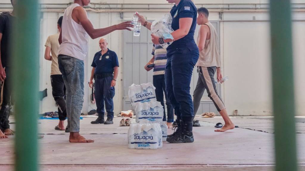 Mitarbeiter der griechischen Küstenwache geben Migranten aus Afrika Wasser, während sie in Agia Port, Chania, Insel Kreta, Schutz suchen. Foto: Giannis Angelakis/AP/dpa