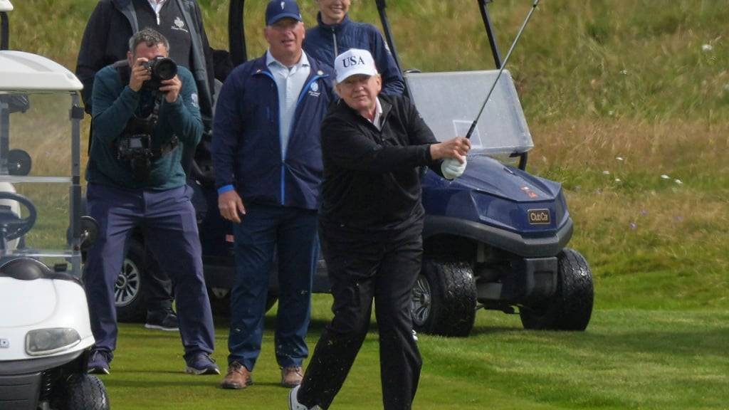 US-Präsident Donald Trump (r) spielt Golf auf dem Trump Turnberry Golfplatz in Turnberry. Trump hat seine fünftägige Privatreise in das Land begonnen. Foto: Alastair Grant/AP/dpa