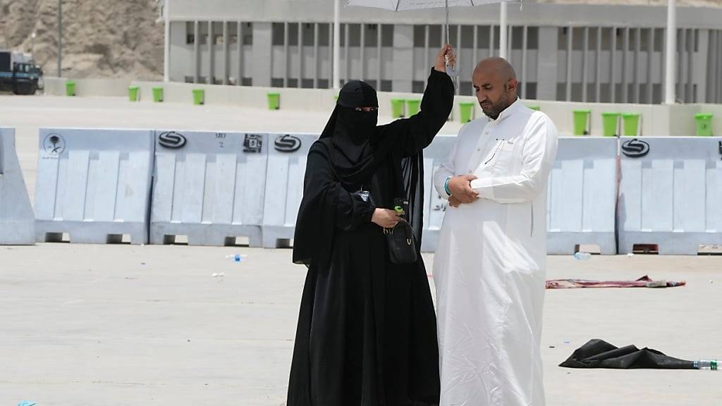 ARCHIV - Eine Frau hält einen Schirm über einen Mann, der sein Gebet am letzten Tag der Hadsch in Mekka in Saudi-Arabien verrichtet. Foto: Amr Nabil/AP/dpa