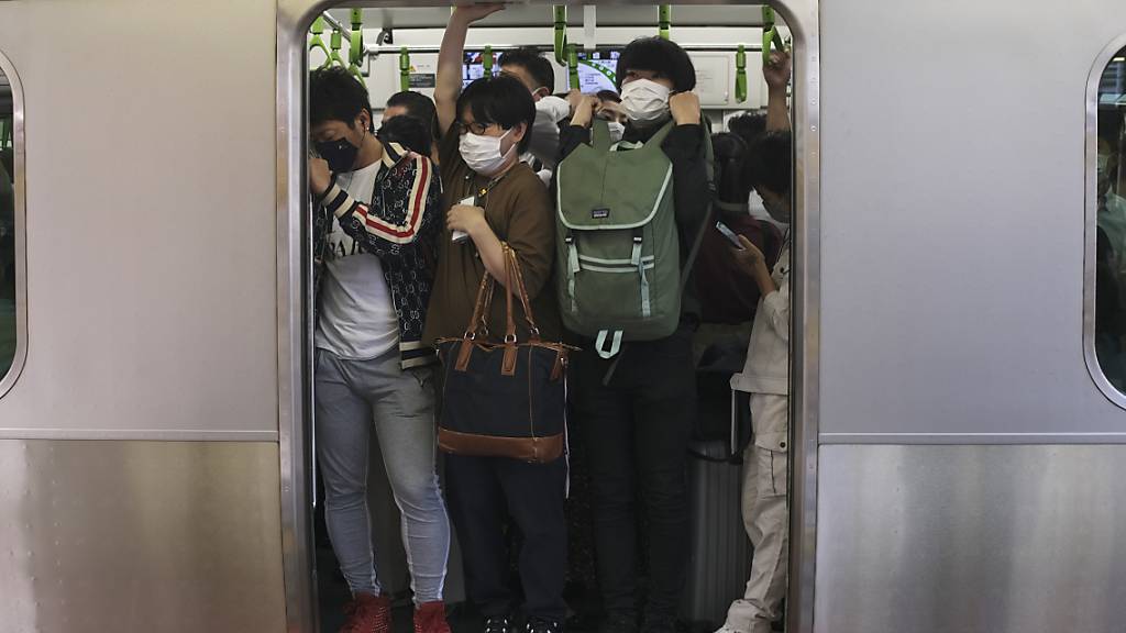 Pendler drängen sich in Tokio in einen Zugwaggon, nachdem ein starkes Erdbeben in der Nacht zum Donnerstag (Ortszeit) die Region Tokio erschüttert und Züge und U-Bahnen vorübergehend lahmgelegt hat. Bei dem Erdbeben sind laut Berichten japanischer Medien mindestens 32 Menschen verletzt worden. Foto: Kiichiro Sato/AP/dpa