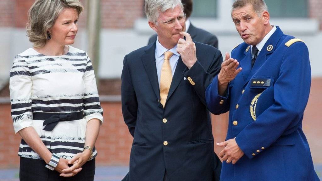 Ein Polizeioffizier redet mit dem Königspaar in Charleroi über den Tathergang.