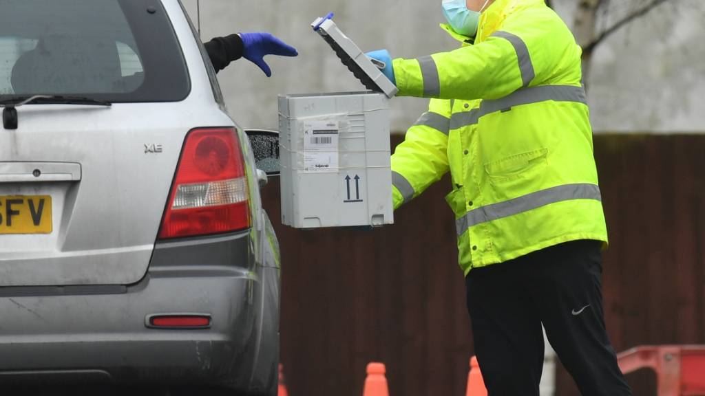 ARCHIV - In einem Corona-Testzentrum wirft ein Fahrer aus dem Auto ein Testkit in eine Box. Die Bürger in England sollen sich bald zweimal pro Woche kostenlos auf das Coronavirus testen lassen können. Foto: Jacob King/PA Wire/dpa