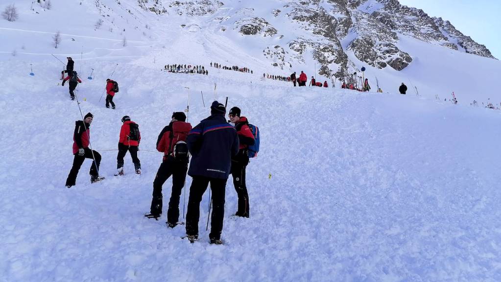 Rettungskräfte sind am Lawinenkegel im Einsatz. Im beliebten Skiort Sölden verschüttete eine Lawine fünf Wintersportler auf einer gesicherten Piste. Sie wurden lebend geborgen.