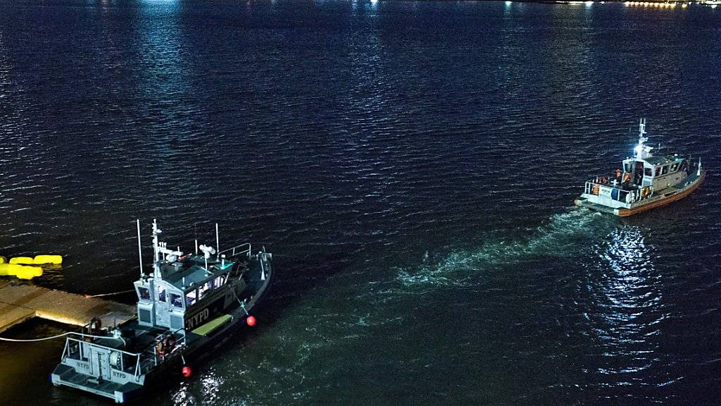 Polizeiboot bei dem über Wasser gehaltenen Helikopter im East River