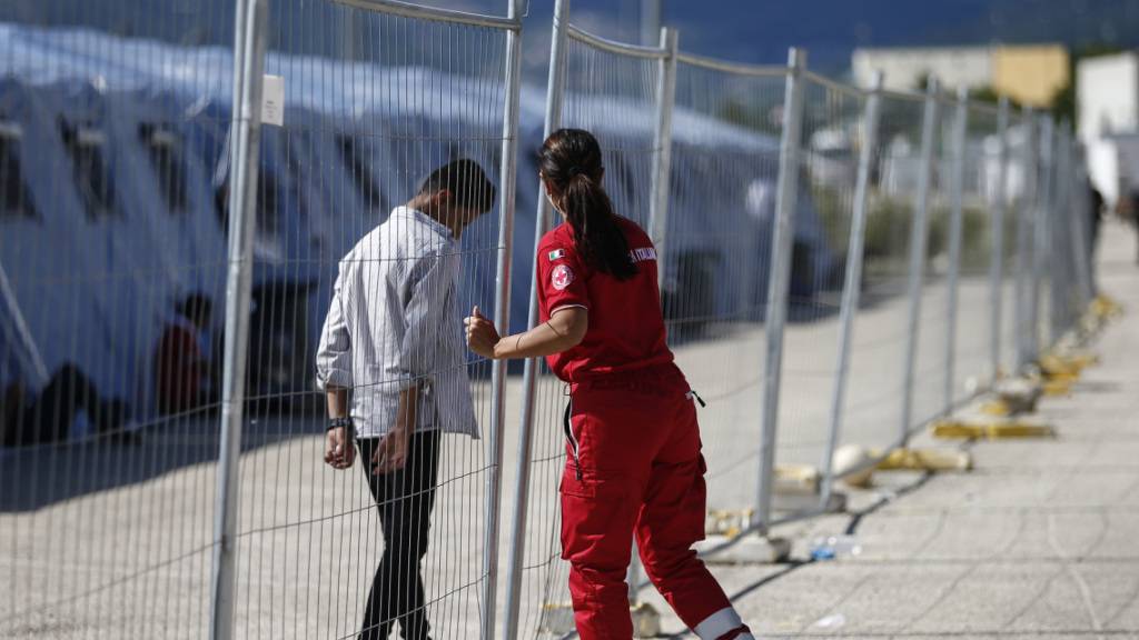 Ein geflüchteter Afghane geht an einem Zaun in einem Einsatzzentrum des italienischen Roten Kreuzes, Croce Rossa Italiana (CRI) in Avezzano. In dem Einsatzzentrum werden mit Hilfe der Armee und des Zivilschutzes afghanische Geflüchtete aufgenommen. Foto: Cecilia Fabiano/LaPresse via ZUMA Press/dpa