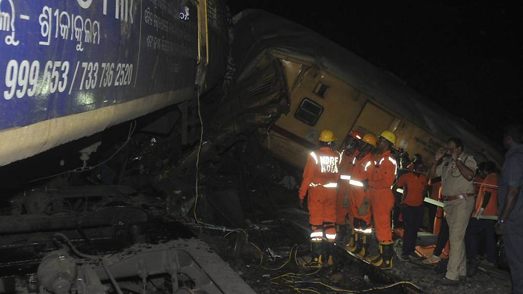dpatopbilder - Rettungskräfte stehen nach dem Zusammenstoß zweier Personenzüge am Unfallort in Indien. Foto: Uncredited/AP/dpa