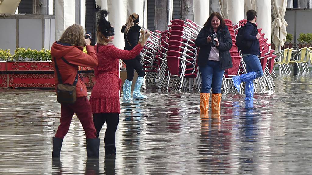 Menschen auf dem überfluteten Markusplatz. Wegen Unwettern und starker Winde droht der norditalienischen Lagunenstadt Hochwasser. Foto: Matteo Tagliapietra/LaPresse/dpa