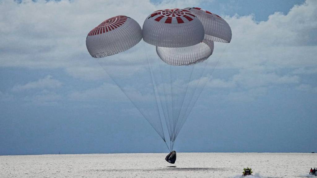 Eine SpaceX-Kapsel mit vier Personen an Bord geht vor der Küste Floridas mit Fallschirmen in den Atlantik nieder. Foto: Uncredited/SpaceX via AP/dpa - ACHTUNG: Nur zur redaktionellen Verwendung und nur mit vollständiger Nennung des vorstehenden Credits bis 14 Tage nach Sendedatum.