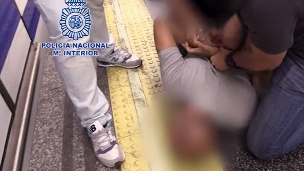 Spanische Polizeibeamte in Zivil nehmen den mutmasslichen Filmer an einer U-Bahnstation in Madrid fest. (Screenshot)