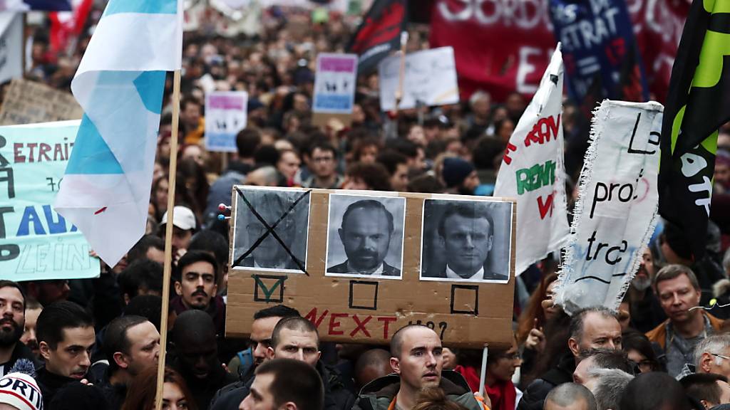 Demonstranten in Paris fordern den Rücktritt von Premierminister Edouard Philippe und Präsident Macron. Links auf dem Plakat ist Jean-Paul Delevoye abgebildet, der Rentenbeauftragte der Regierung trat am Montag nach Enthüllungen über zahlreiche Nebenjobs zurück.