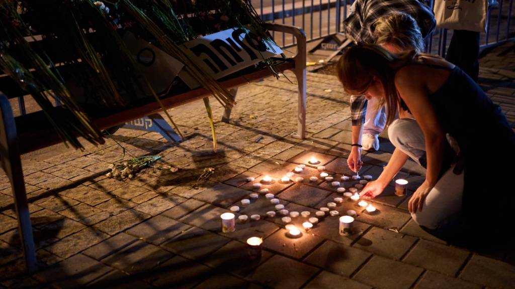 dpatopbilder - Eine Frau zündet vor dem gerichtsmedizinischen Institut Abu Kabir Kerzen an, in dem die Identifizierung der Leichen durchgeführt wird, die von der Hamas im Gazastreifen festgehalten und getötet wurden. Foto: Emilio Morenatti/AP/dpa