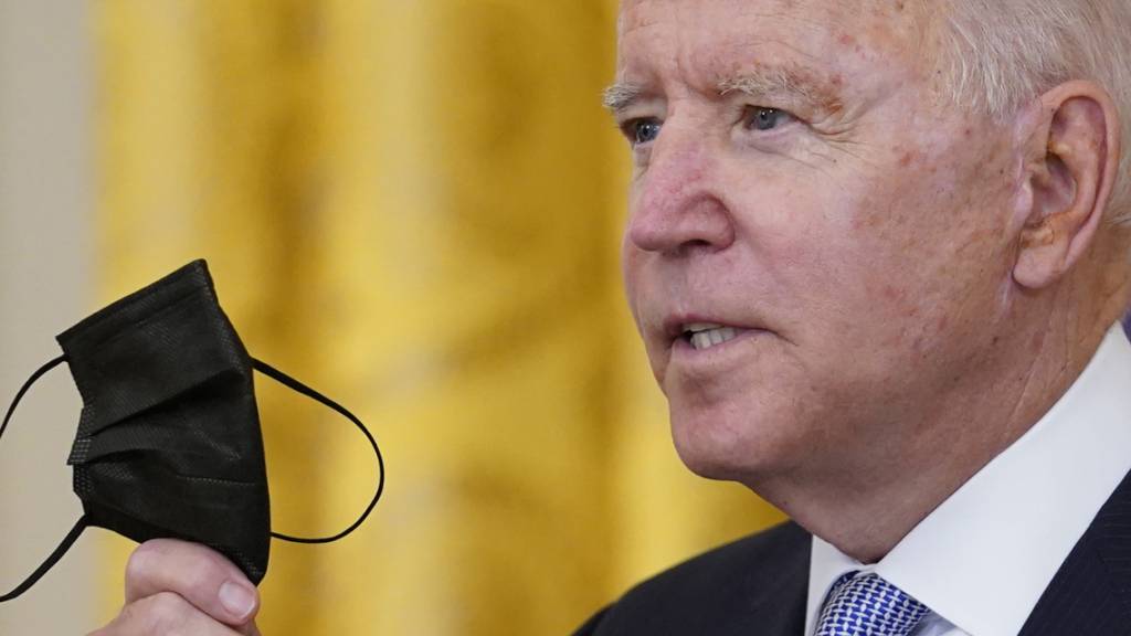 Joe Biden, Präsident der USA, hält seinen Mund-Nasen-Schutz während er im Weißen Haus über die Impfvorschriften für Bundesbedienstete spricht. Foto: Susan Walsh/AP/dpa