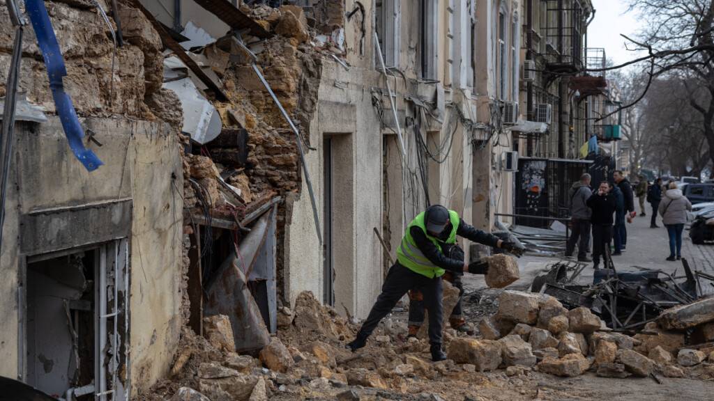 ARCHIV - Ein städtischer Arbeiter räumt die Trümmer eines Wohnhauses auf, das nach einem russischen Drohnenangriff beschädigt wurde. Foto: Oleg Grekov/AP/dpa