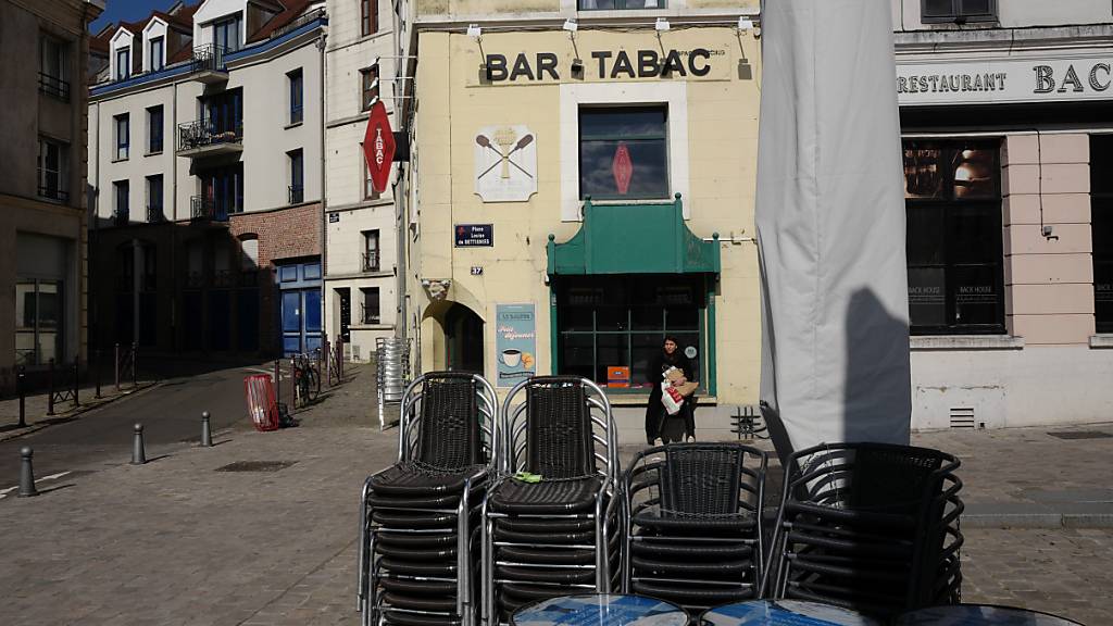 Stühle sind in einer leeren Fußgängerzone vor einem Café aufeinandergestapelt. Frankreich verhängt im Kampf gegen die Corona-Pandemie regionale Ausgangsbeschränkungen. Foto: Michel Spingler/AP/dpa