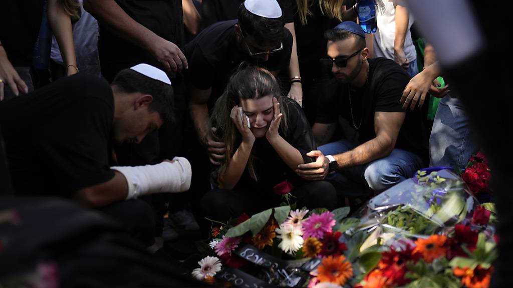 Trauernde versammeln sich um das Grab einer Frau, die auf einem Musikfestival getötet worden war. Foto: Francisco Seco/AP/dpa