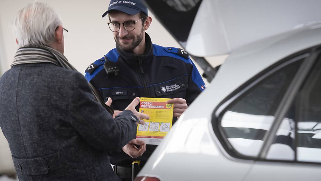 Ein Mitarbeiter der Bundeszollverwaltung verteilt an der schweizerisch-italienischen Grenze Broschüren über die Präventionskampagne des Bundesamtes für Gesundheit (BAG) gegen die Ausbreitung des Coronavirus COVID-19.