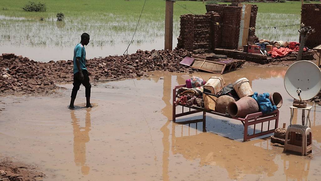 ARCHIV - Eine Person watet nach schweren Regenfällen durch Hochwasser in der Nähe der Überreste seines Hauses. Foto: Marwan Ali/AP/dpa