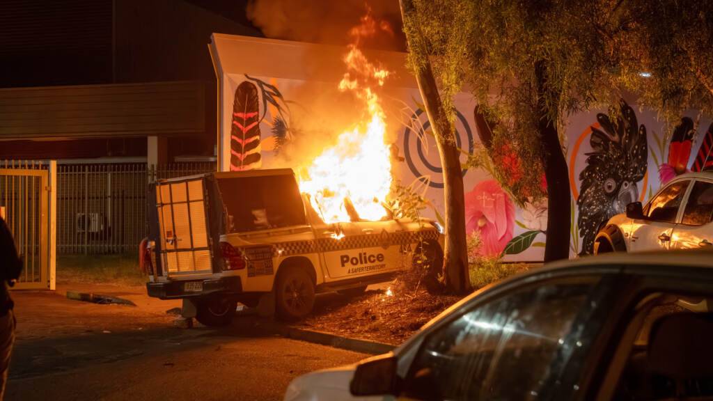 Ein Polizeifahrzeug brennt vor dem Krankenhaus in Alice Springs, wo ein Mann, der verdächtigt wird, ein fünfjähriges Mädchen getötet zu haben, unter Polizeibewachung steht. Foto: Rhett Hammerton/AAP Image/AP/dpa