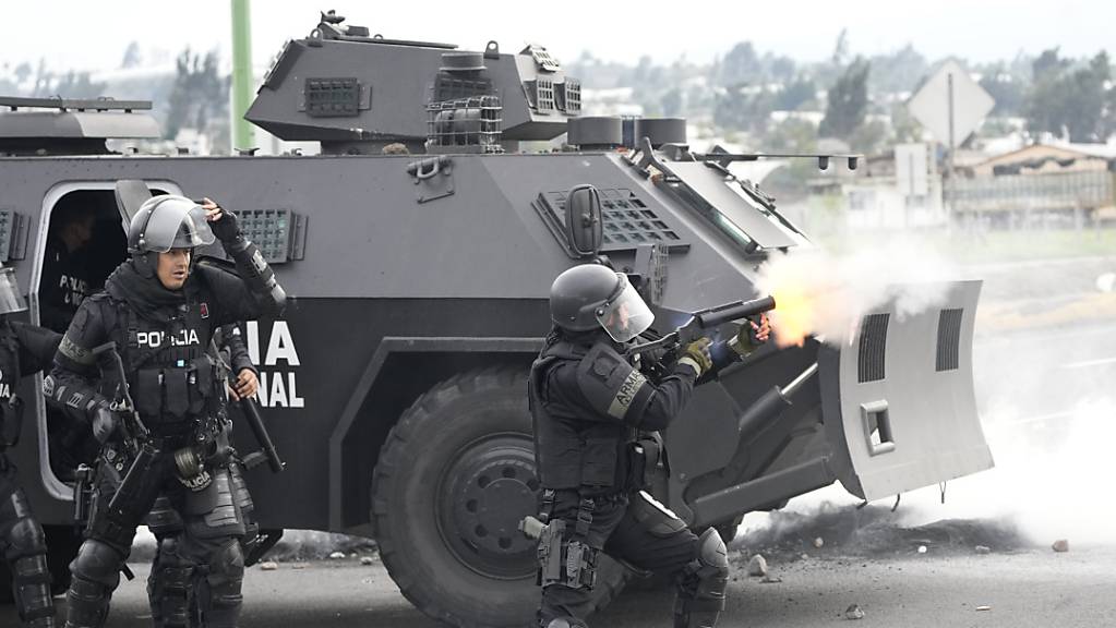 Ein ecuadorianischer Polizist feuert Tränengas auf Demonstranten ab.