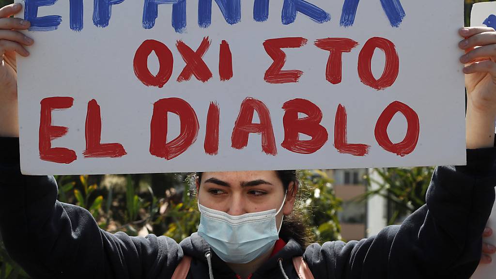 Eine Demonstrantin hält ein Schild mit der Aufschrift «Friedlich gegen El Diablo» vor dem nationalen Rundfunkgebäude Zyperns in die Höhe. Foto: Petros Karadjias/AP/dpa