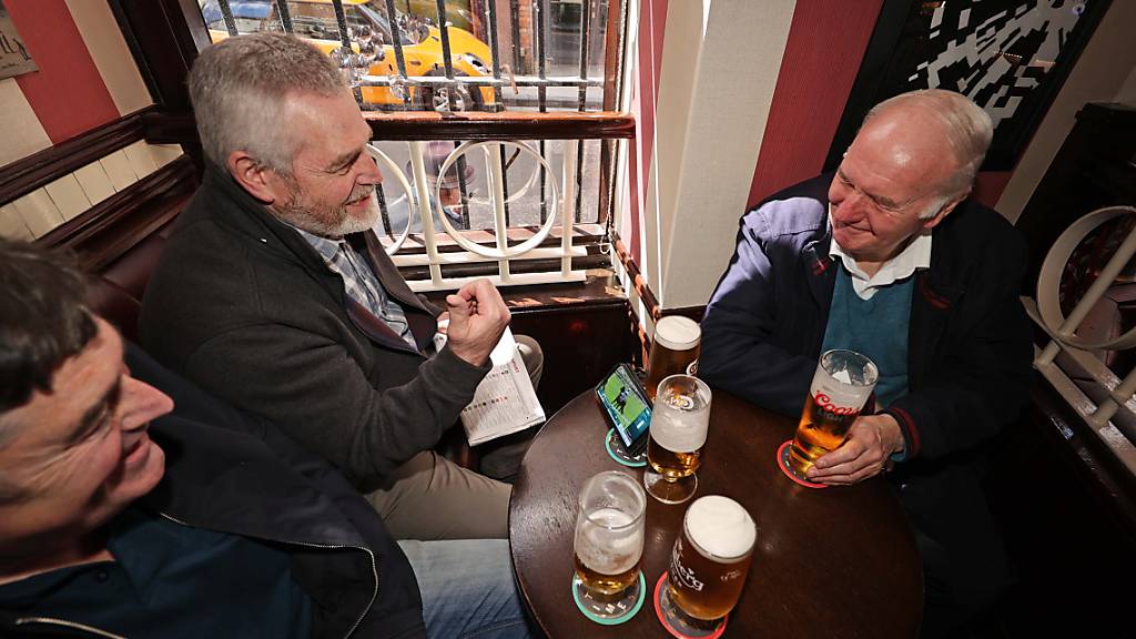 Drei Männer nutzen die Corona-Lockerungen für einen Pub-Besuch in Belfast. Foto: Liam Mcburney/PA Wire/dpa