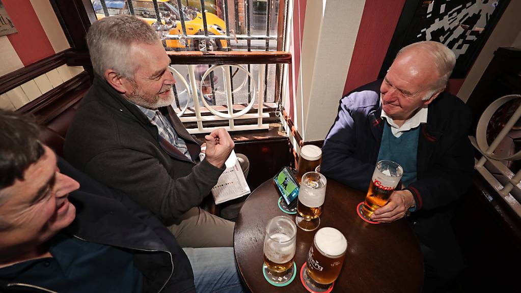 Drei Männer nutzen die Corona-Lockerungen für einen Pub-Besuch in Belfast. Foto: Liam Mcburney/PA Wire/dpa