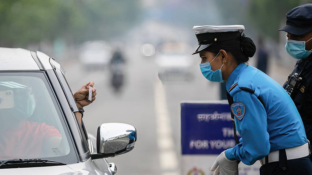 Polizisten kontrollieren die Fahrzeugpapiere am vierten Tag des landesweiten Lockdowns. Angesichts rasch steigender Corona-Fallzahlen streicht Nepal Flugverbindungen für rund zwei Wochen. Foto: Prabin Ranabhat/SOPA Images via ZUMA Wire/dpa