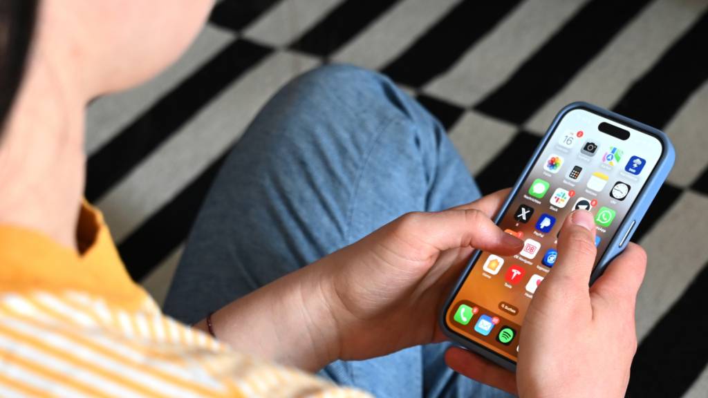 SYMBOLBILD - Eine Jugendliche sitzt auf dem Boden und nutzt ein Smartphone - auf dem Display sind verschiedene Apps zu sehen. Foto: Elisa Schu/dpa