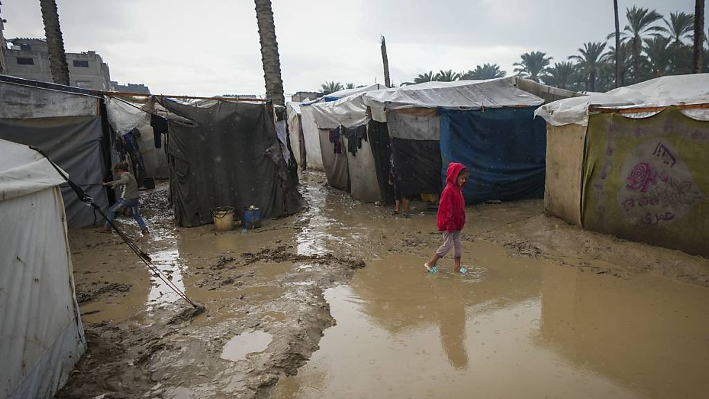 Ein junges Mädchen in einer überschwemmten Straße. Foto: Abdel Kareem Hana/AP/dpa