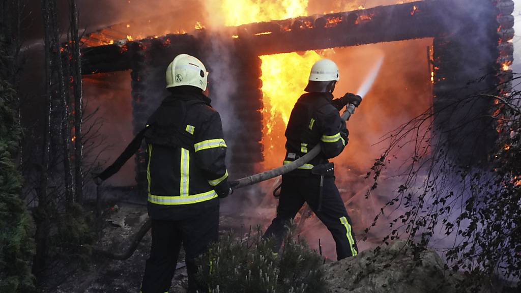 ARCHIV - Feuerwehrleute löschen ein Feuer, nachdem ein Haus von russischem Beschuss getroffen wurde. Foto: Andrii Marienko/AP/dpa