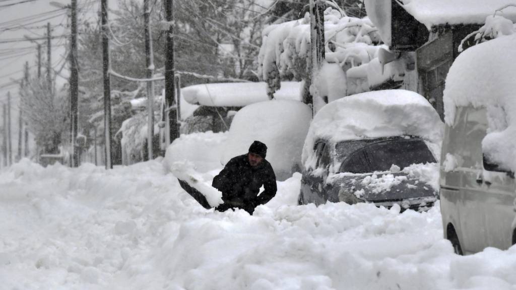 Ein Mann schaufelt Schnee, um sein Auto zu befreien. Bei Schneechaos mit starken Winden mussten am Wochenende in dem Balkanland mehr als 1000 Orte ohne Strom auskommen. Foto: Mehmed Aziz/AP/dpa
