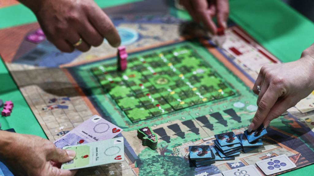 Menschen spielen auf der Publikumsmesse «Spiel Essen» das Brettspiel «Roxane». Foto: Oliver Berg/dpa