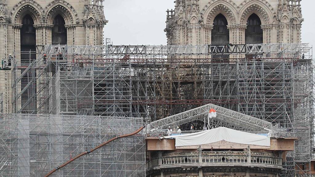 Arbeiter auf einer Plattform demontieren beschädigte Gerüstteile an der Kathedrale Notre-Dame.