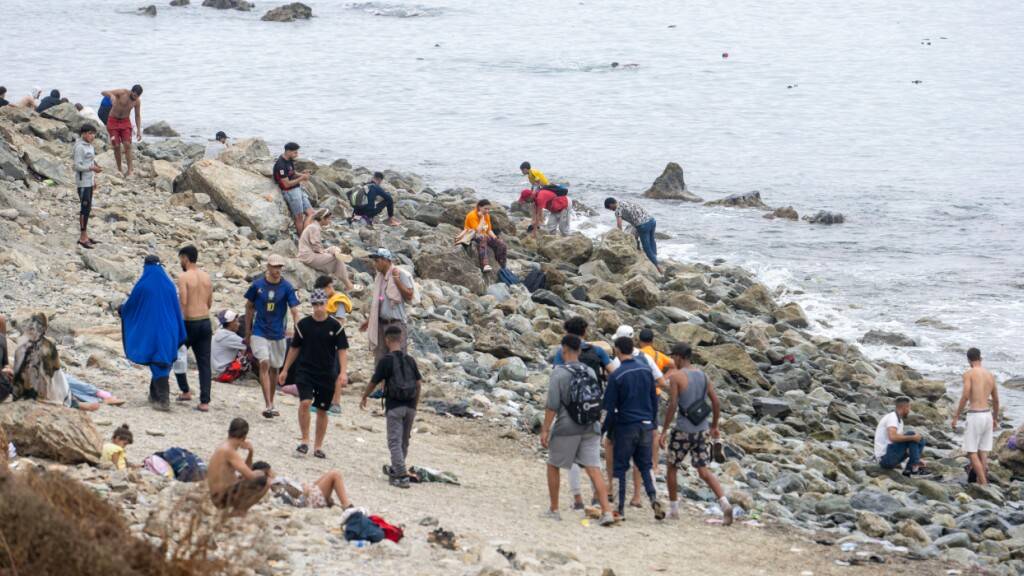 Menschen gehen am Strand entlang, während sie versuchen, von der marokkanischen Stadt Fnideq im Norden in die spanische Enklave Ceuta zu gelangen. Foto: STR/AP/dpa