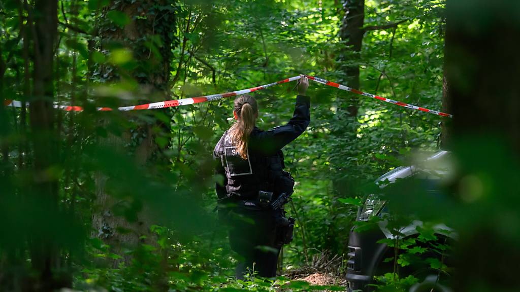 Eine Polizistin hält in einem Wald Absperrband hoch. Bei der Suche nach der vermissten neunjährigen Valeriia hat die Polizei im sächsischen Döbeln eine Leiche gefunden. Foto: Robert Michael/dpa