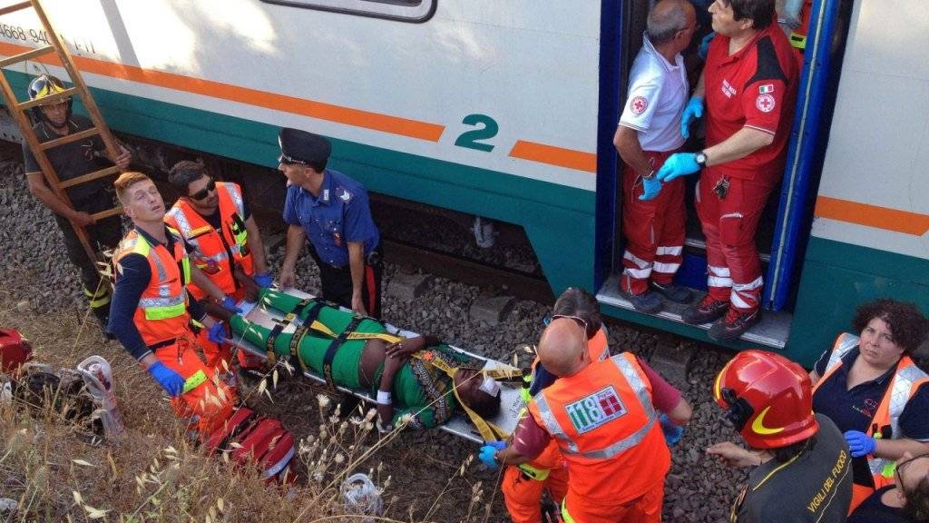 Rettungskräfte helfen einer Frau, die bei einer Zugkollision in Süditalien verletzt wurde.