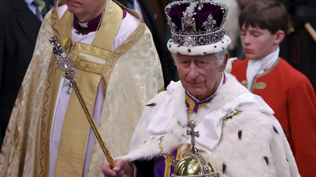 ARCHIV - Großbritanniens König Charles III. verlässt nach der Krönungszeremonie mit der Imperial State Crown, einem Zepter und dem Reichsapfel die Westminster Abbey. Foto: Phil Noble/AP/dpa