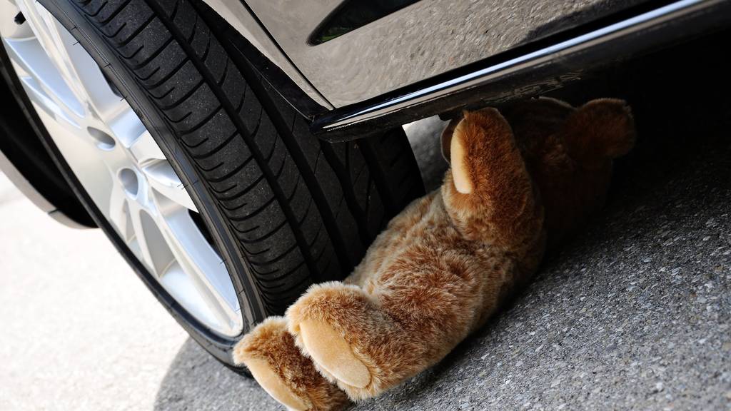 Teddy under car tires, symbolic car accident with playing children