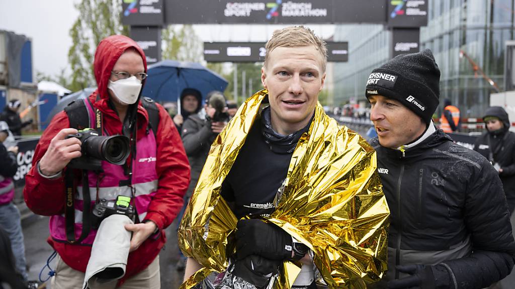 Der Schweizer Meister Patrik Wägeli, eingehüllt in die Kälteschutzfolie, nimmt die Gratulation von Viktor Röthlin entgegen