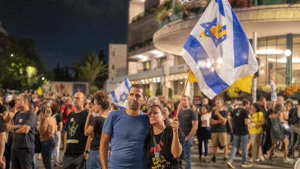 Israelis halten Fahnen während eines Marsches in Jerusalem und fordern einen Waffenstillstand, die Freilassung der Geiseln und ein Ende des Krieges. Foto: Ilia Yefimovich/dpa