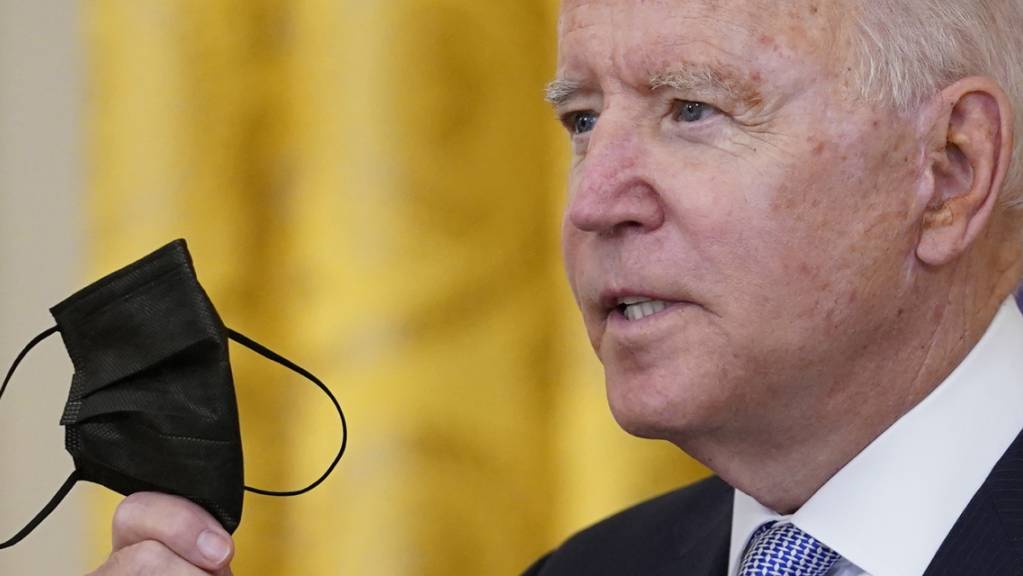 Joe Biden, Präsident der USA, hält seinen Mund-Nasen-Schutz während er im East Room des Weissen Hauses in Washington über die Impfvorschriften für Bundesbedienstete spricht.