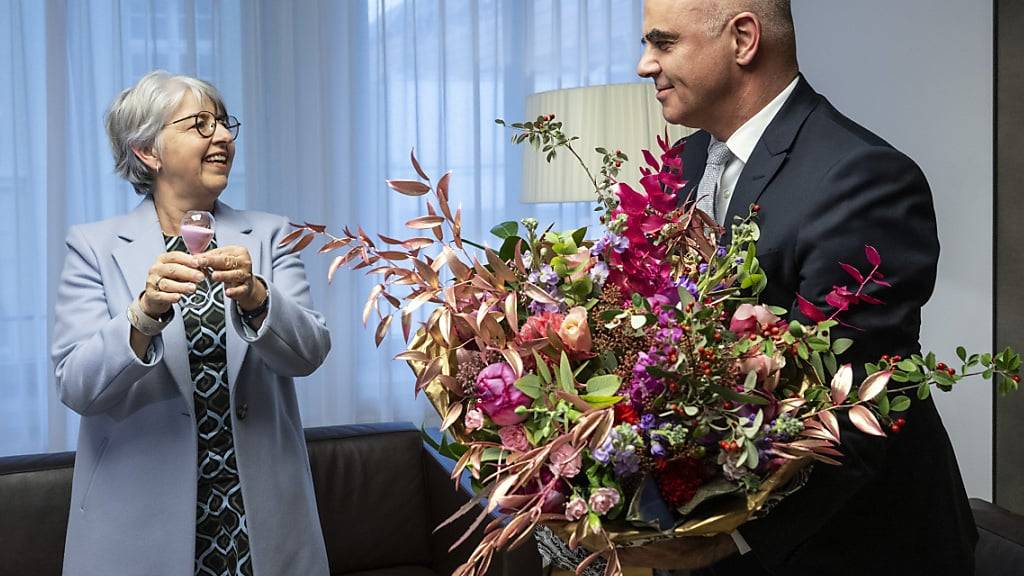 Bundespräsident Alain Berset übergibt seiner Nachfolgerin Bundesrätin Elisabeth Baume-Schneider einen Blumenstrauss und eine Sanduhr.