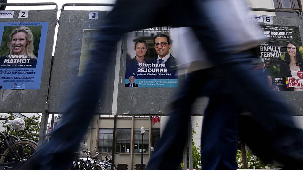 ARCHIV - Menschen gehen an Wahlplakaten für die bevorstehenden Parlamentswahlen vorbei. Foto: Christophe Ena/AP/dpa