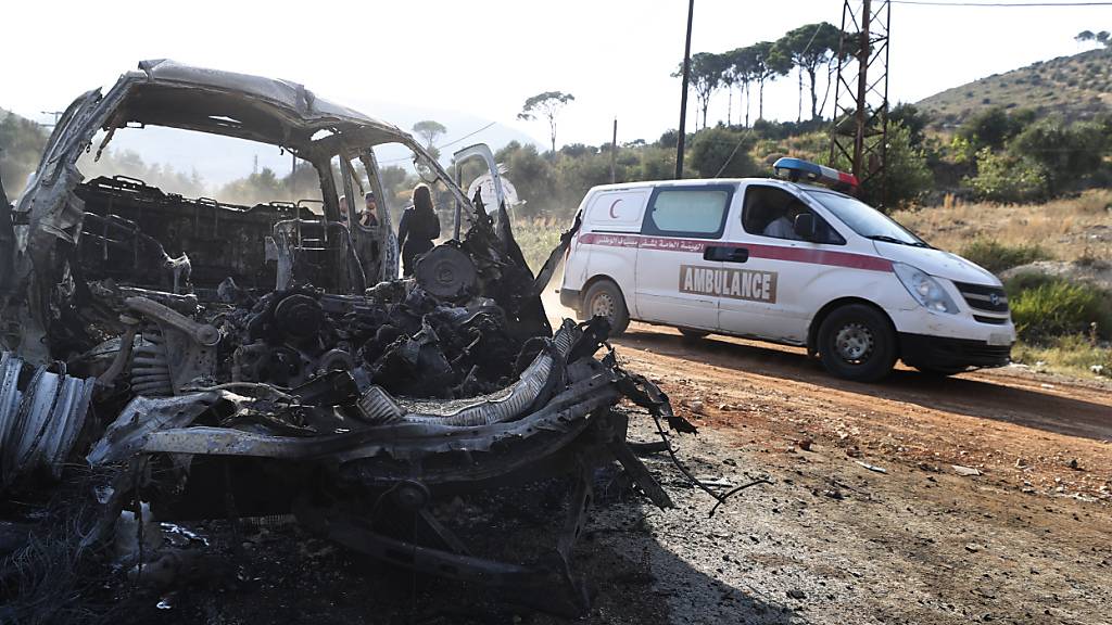 Ein Krankenwagen fährt an einem ausgebrannten Fahrzeug in der Provinz Hama in Zentralsyrien vorbei. Foto: Omar Sanadiki/AP/dpa