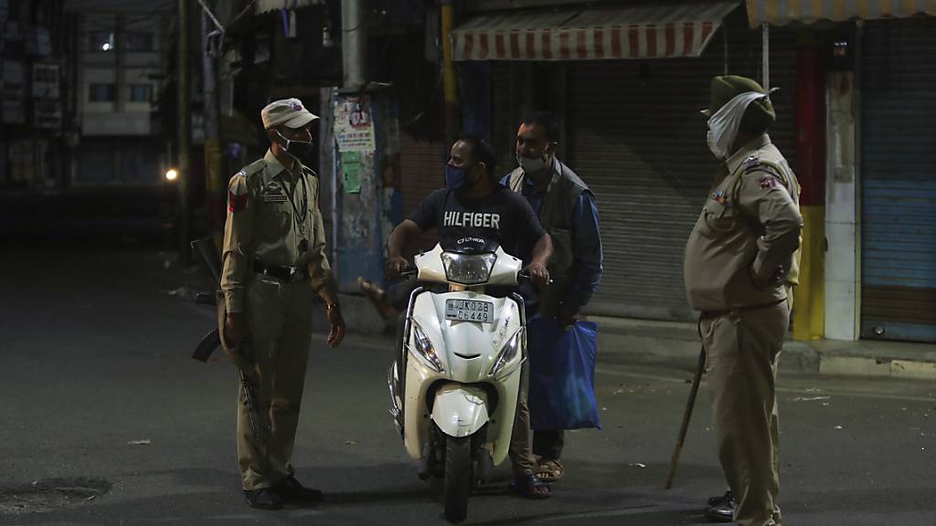 Polizisten kontrollieren einen Rollerfahrer: Dutzende Städte in Indien haben als Maßnahme zur Eindämmung der Coronavirus-Pandemie Ausgangssperren verhängt. Foto: Channi Anand/AP/dpa