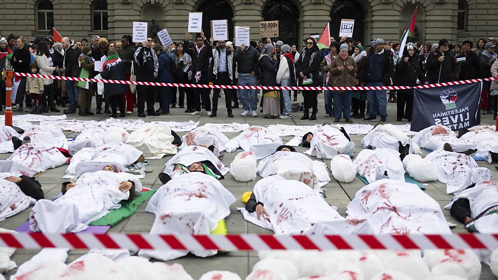 Demonstranten liegen bei einer Solidaritätskundgebung für Gaza als symbolische Leichen unter einem weissen Tuch auf dem Bundesplatz in Bern.