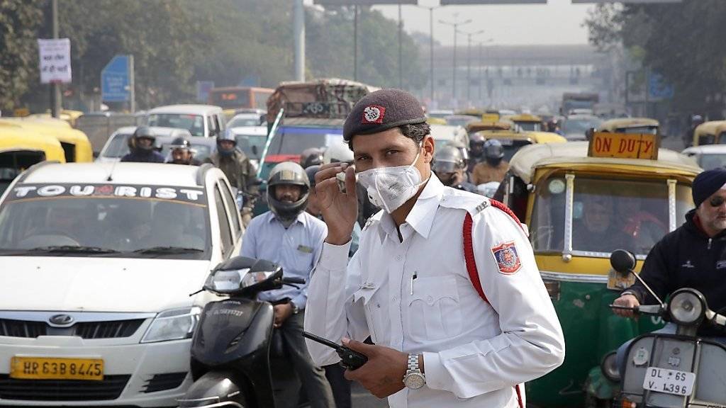 Ein Polizist in Indiens Hauptstadt Neu Delhi schützt sich mit einer Maske vor den Autoabgasen. Wegen des Smogs gilt ein Fahrverbot für Autos - abwechslungsweise für solche mit geraden und mit ungeraden Autonummern. Die Regel wird befolgt - was hier nicht auf den ersten Blick ersichtlich ist.