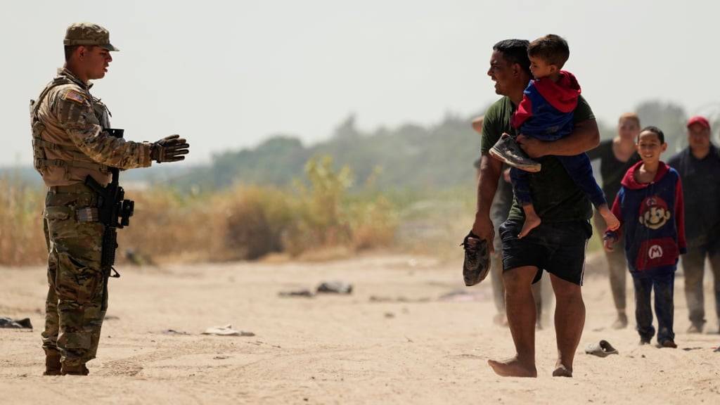 ARCHIV - Ein Wachmann gibt Migranten, die den Rio Grande in Mexiko in die USA überquert haben, Anweisungen. Foto: Eric Gay/AP/dpa